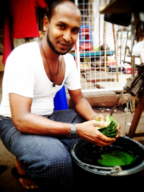 A man washes leaves to wrap betel nuts in, for selling.
